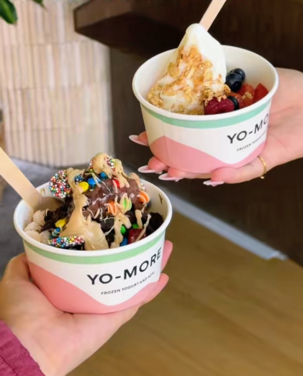 Two Yo More frozen yogurt cups loaded with toppings